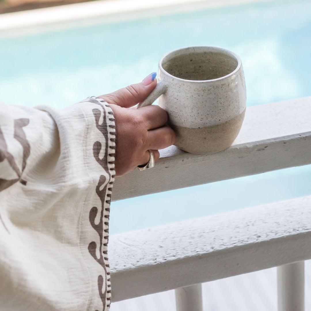 hand holding mug of tea with pool in the back ground