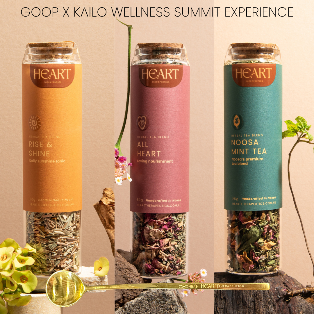 Three glass jars with different tea blends labeled 'Rise and Shine', 'All Heart', and 'Noosa Mint Tea' from the GOOP x Kailo Wellness Summit Experience collection. Each jar contains loose tea leaves and the third includes a gold-colored tea spoon.