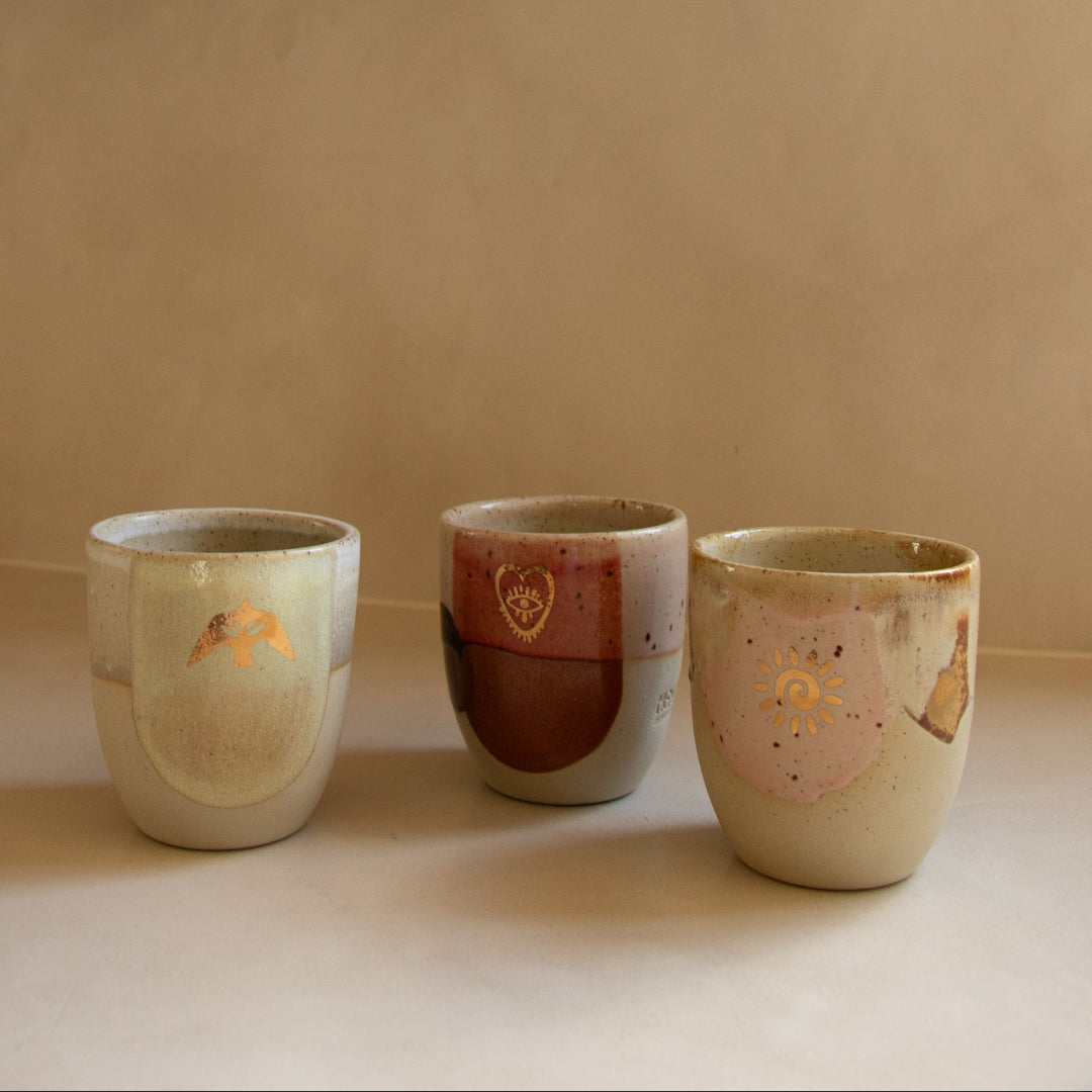 Three ceramic cups with different designs on a plain background