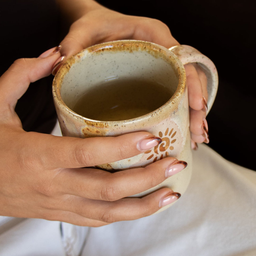 Person holding a ceramic mug with a floral design against a dark background
