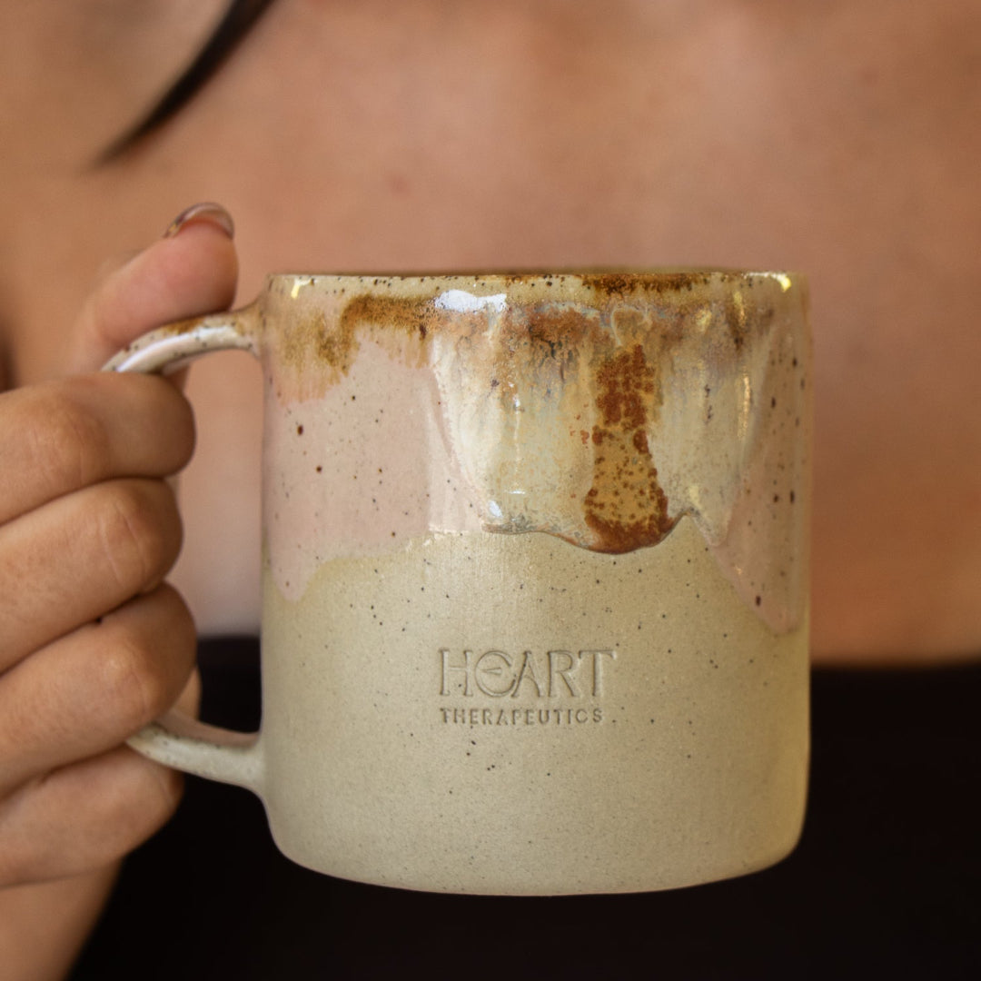 Person holding a ceramic mug with 'HEART' branding
