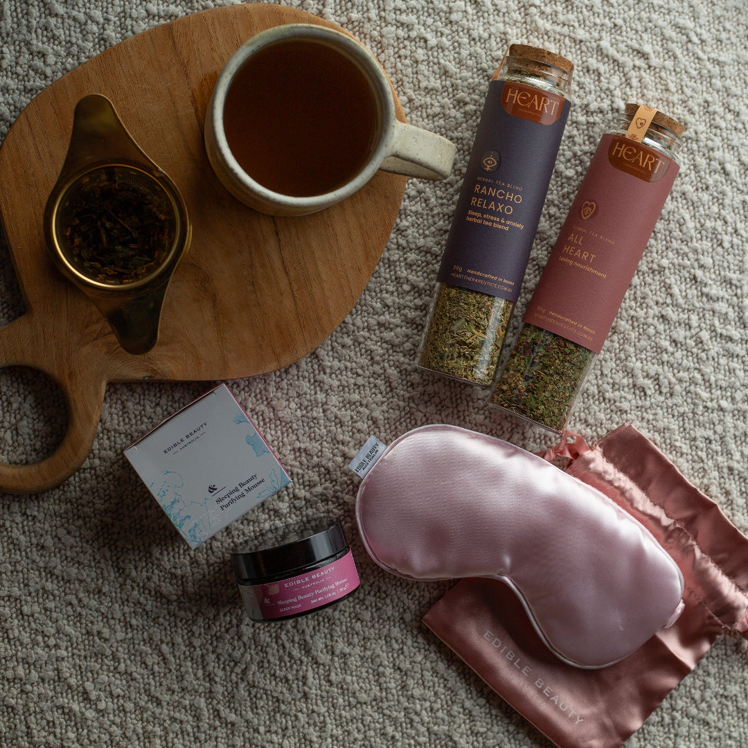 Tea-making set with a cup, tea leaves, and sleep mask on a textured surface