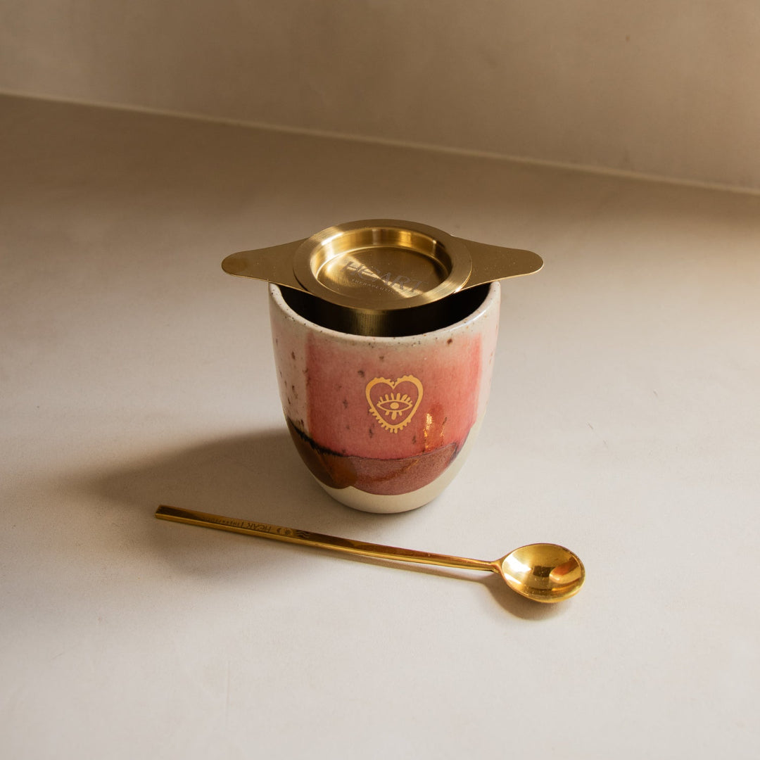 Ceramic container with gold lid and spoon on a beige surface