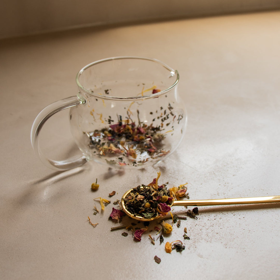 Clear glass mug with tea leaves on a light surface
