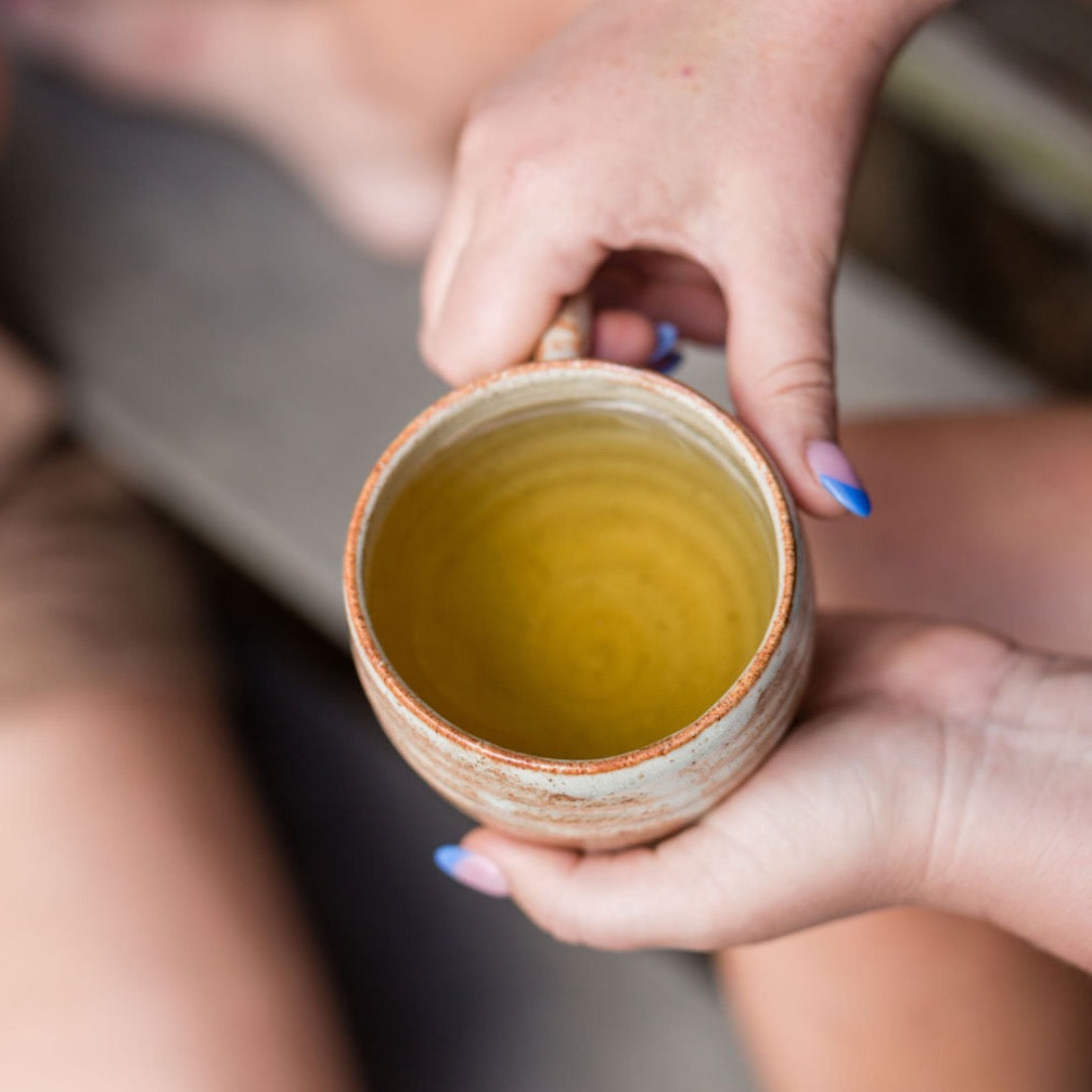 Hands holding a cup of herbal tea