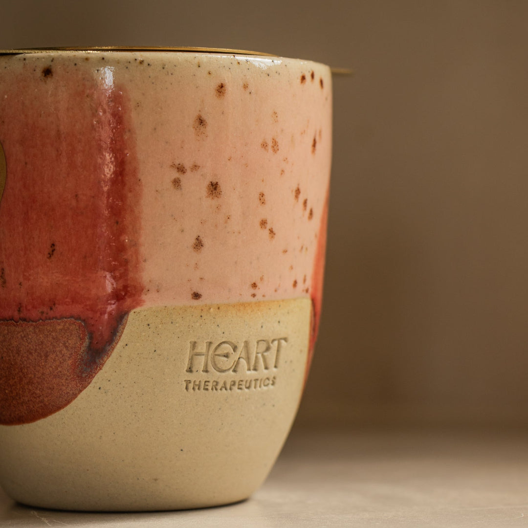Ceramic mug with speckled design and 'Heart Therapeutics' branding on a neutral background