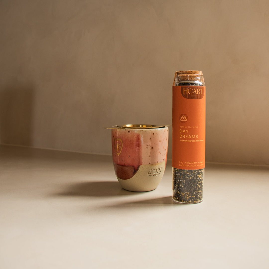 Ceramic mug and cylindrical container with 'HEART' branding on a neutral background