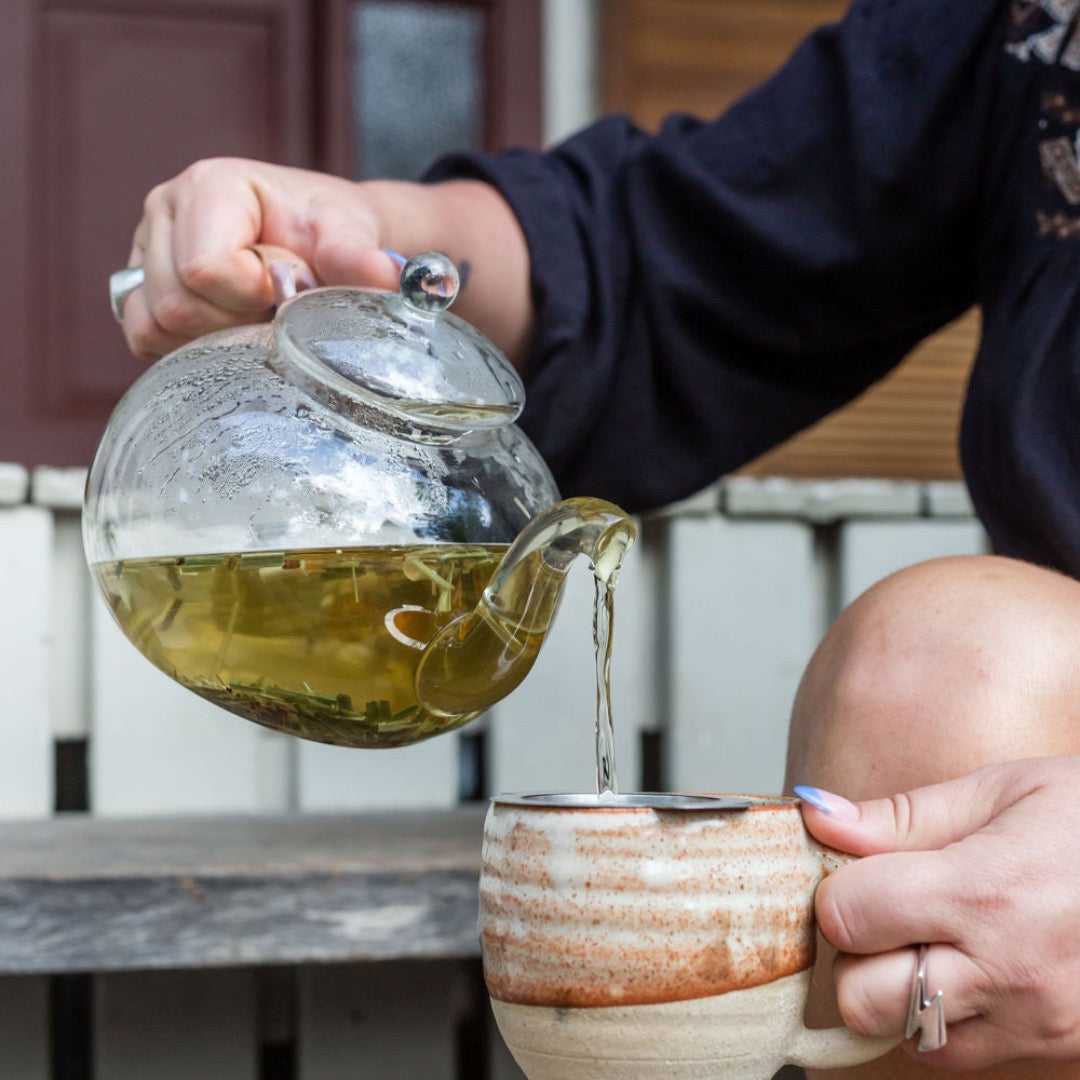 Pouring a cup of herbal tea from a glass tea pot