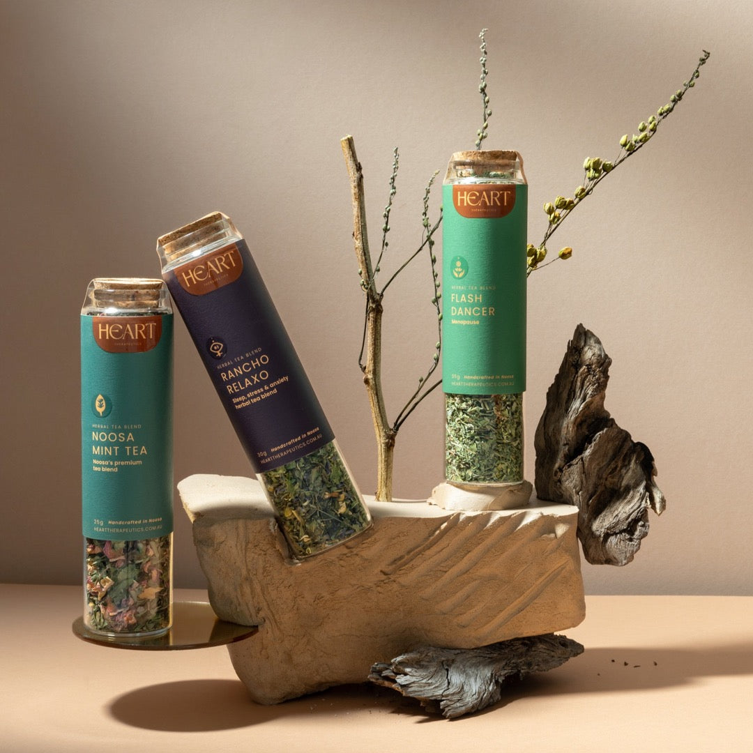 3 glass jars of herbal tea balancing on a rock