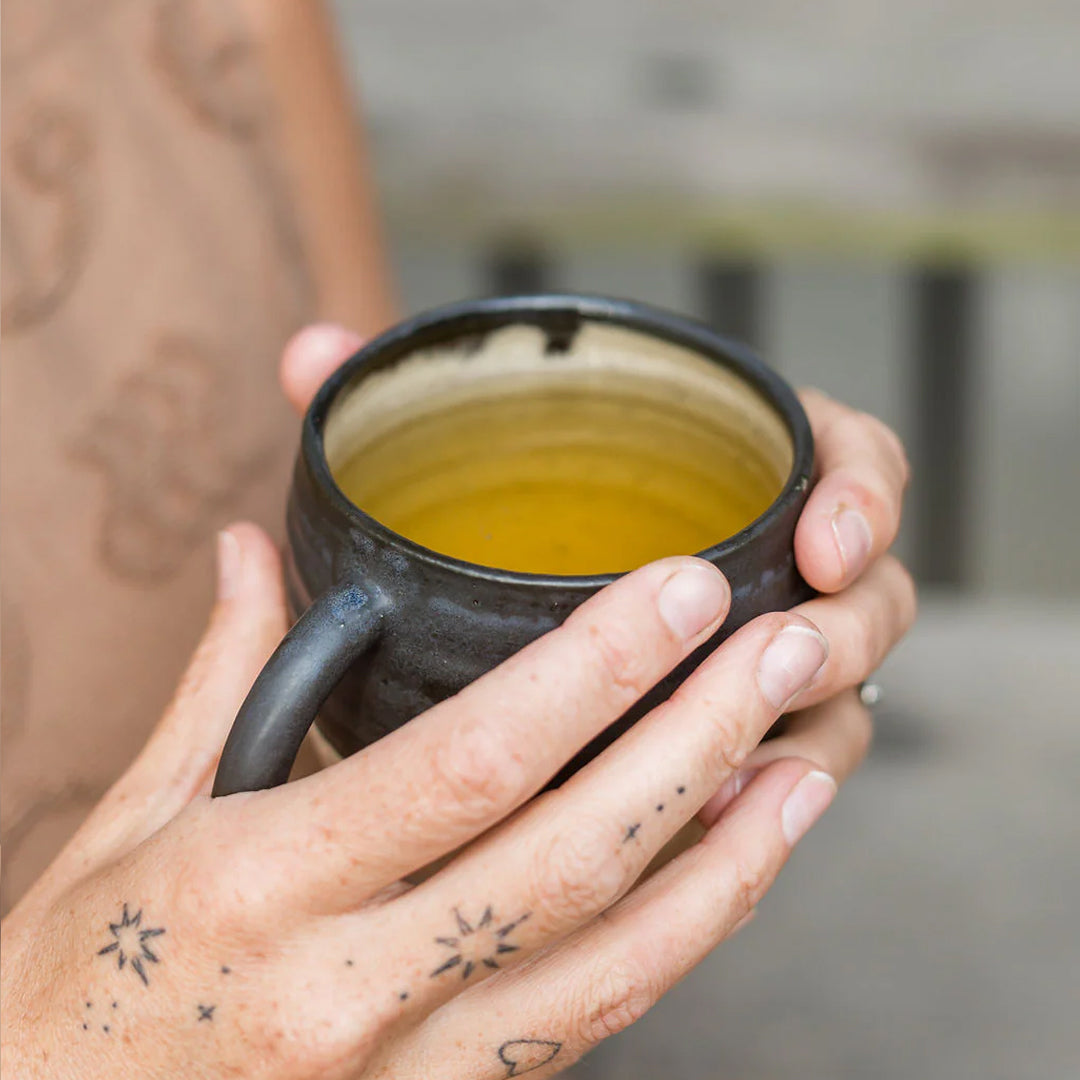 hands holding ceramic cup of tea