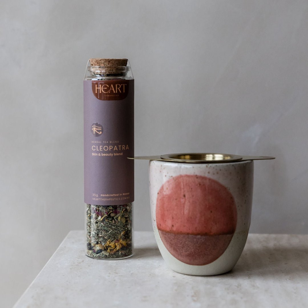 one jar of herbal tea and a gold tea infuser in a ceramic cup